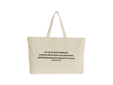 A natural canvas tote bag with black printed text of a Bible verse from Ephesians 2:10, shown against a plain white background.