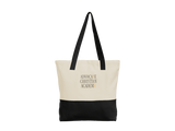 A canvas tote bag with a cream upper section, black bottom panel, and black shoulder straps. The front features a 5"x3.125" aADVOCATE CHRISTIAN ACADEMY logo in gold and black lettering, set against a plain white background.