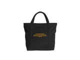 A black tote bag with black handles, trim, and base, featuring a quote from Ephesians in gold on the back.