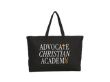 A black canvas tote bag with long handles, featuring the text 'ADVOCATE CHRISTIAN ACADEMY' printed in white with gold accents on the front, set against a plain white background.